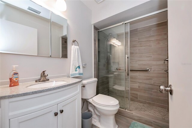 full bath featuring toilet, visible vents, a stall shower, and vanity