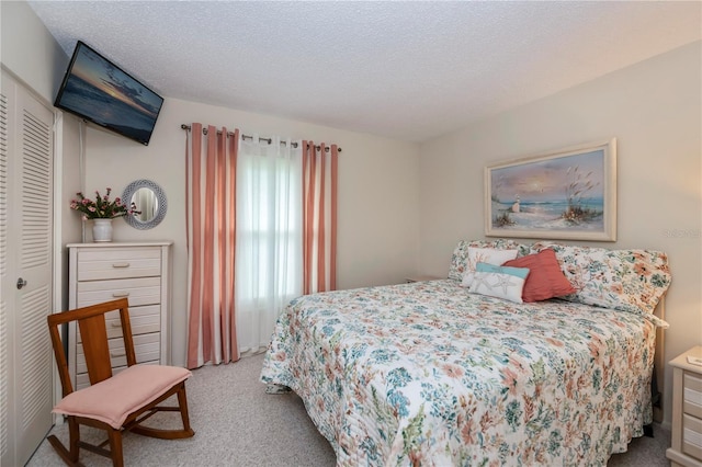 bedroom with a closet, light colored carpet, and a textured ceiling