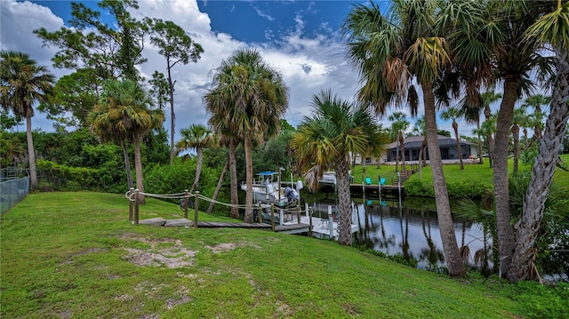 view of dock featuring a water view, a lawn, boat lift, and fence