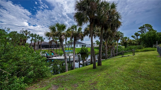 view of dock with a water view, boat lift, and a yard