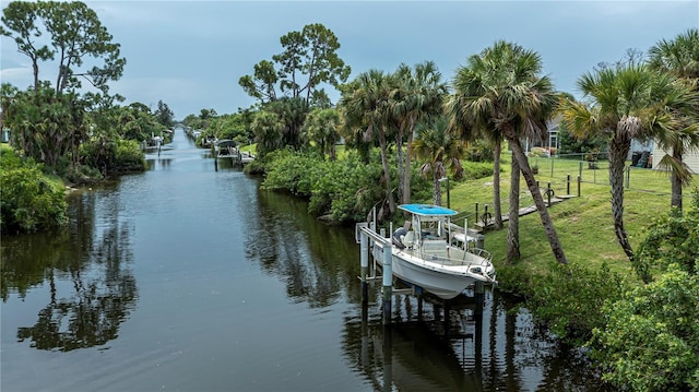 view of dock with a water view, boat lift, and a lawn