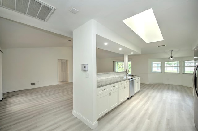 kitchen with backsplash, light hardwood / wood-style floors, stainless steel dishwasher, light stone countertops, and white cabinets