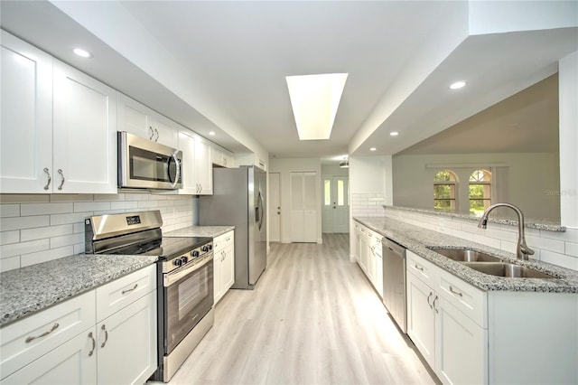 kitchen featuring sink, light hardwood / wood-style flooring, backsplash, and stainless steel appliances