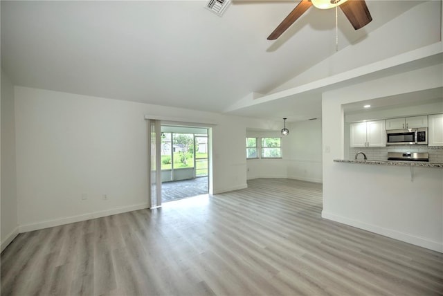 unfurnished living room with light wood-type flooring, high vaulted ceiling, and ceiling fan