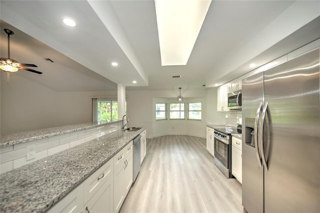 kitchen with backsplash, stainless steel appliances, white cabinetry, light wood-type flooring, and ceiling fan