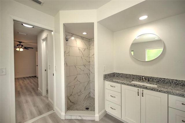 bathroom featuring ceiling fan, tiled shower, hardwood / wood-style floors, and vanity