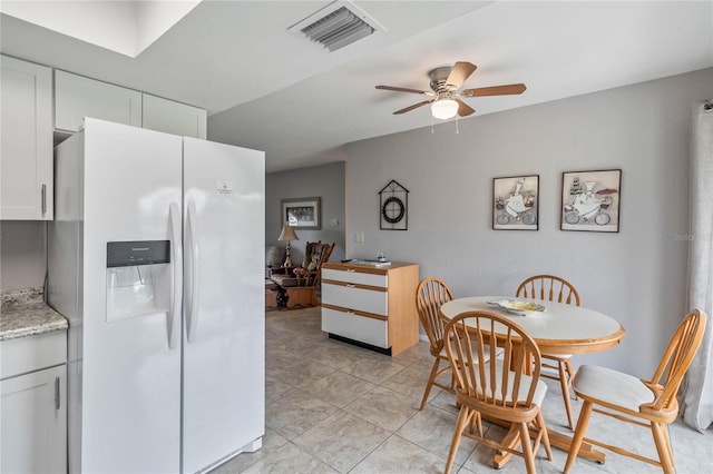 kitchen with white cabinetry, light stone countertops, light tile patterned floors, white refrigerator with ice dispenser, and ceiling fan