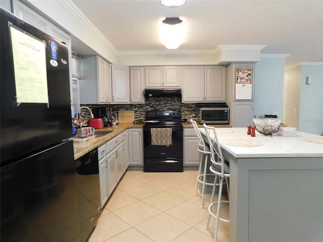 kitchen with a kitchen bar, tasteful backsplash, sink, black appliances, and gray cabinetry