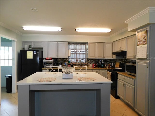 kitchen with electric range, gray cabinets, decorative backsplash, and a kitchen island