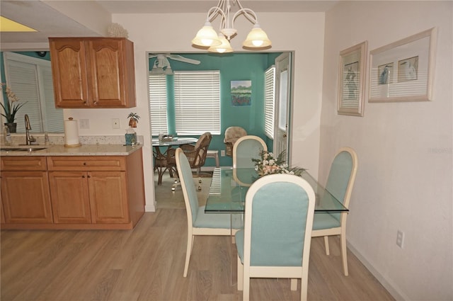 dining area featuring light wood-type flooring, sink, and an inviting chandelier