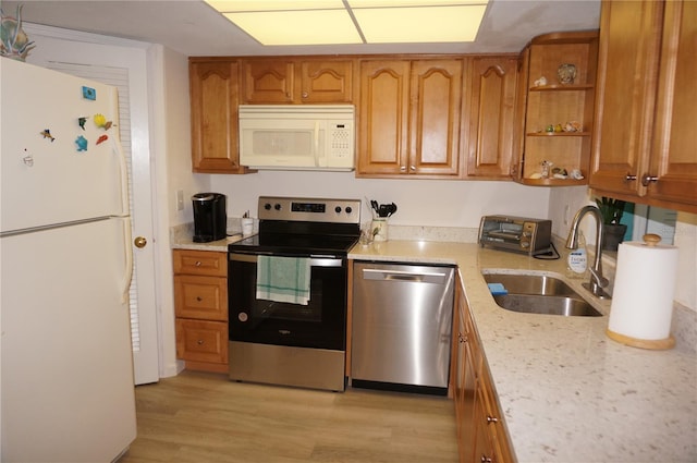 kitchen featuring light hardwood / wood-style floors, appliances with stainless steel finishes, sink, and light stone countertops