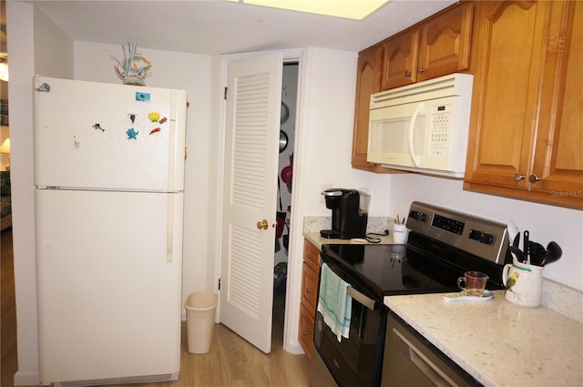 kitchen featuring light stone countertops, light hardwood / wood-style flooring, and white appliances