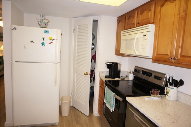 kitchen with brown cabinets, white appliances, light wood finished floors, and light stone countertops