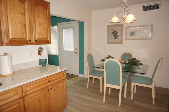 kitchen featuring decorative light fixtures, light hardwood / wood-style flooring, light stone countertops, and a chandelier