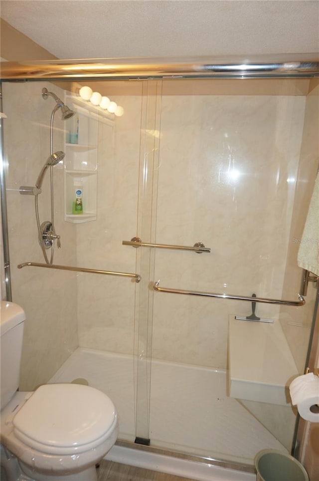 bathroom featuring toilet and a shower with door