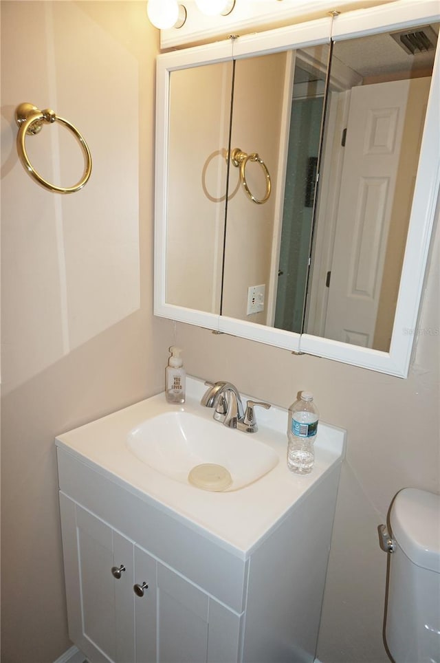 bathroom with toilet, vanity, and visible vents