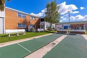 view of property's community with shuffleboard and a yard