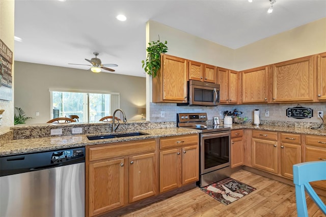 kitchen featuring appliances with stainless steel finishes, backsplash, sink, light wood-type flooring, and ceiling fan