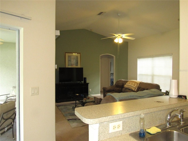 carpeted living room with ceiling fan, vaulted ceiling, and sink