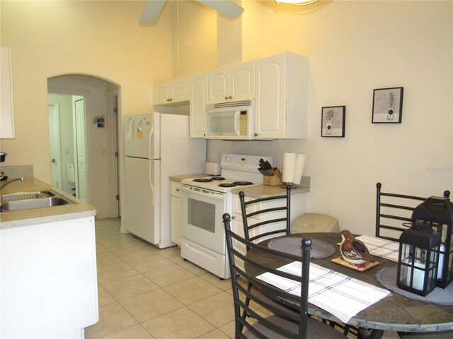 kitchen featuring light tile patterned flooring, sink, a high ceiling, white appliances, and white cabinets