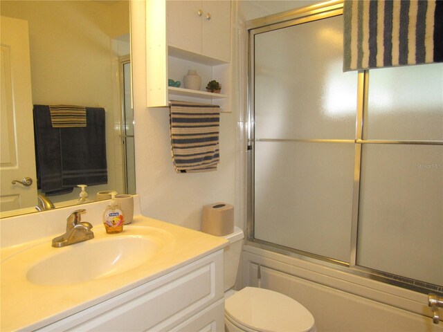 full bathroom featuring vanity, shower / bath combination with glass door, and toilet