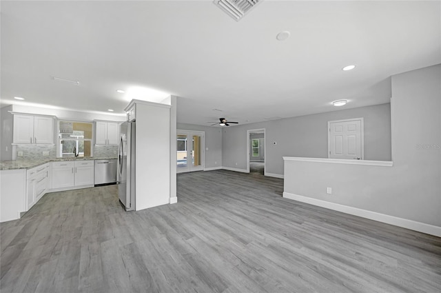 unfurnished living room with baseboards, visible vents, ceiling fan, light wood-style floors, and recessed lighting