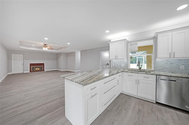 kitchen with sink, dishwasher, backsplash, and light hardwood / wood-style flooring