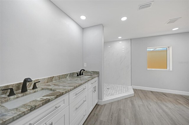 bathroom with vanity, hardwood / wood-style floors, and tiled shower