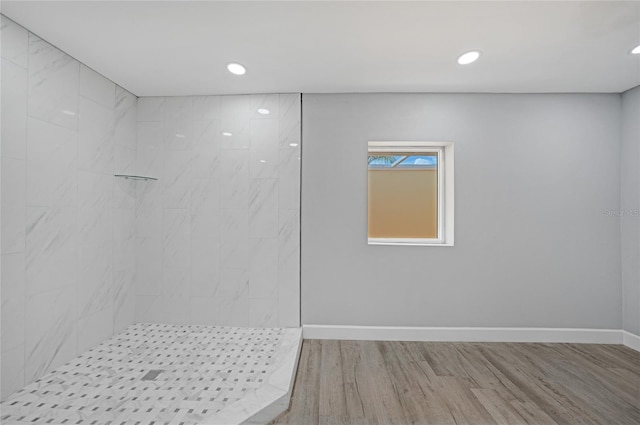 full bathroom with recessed lighting, a tile shower, baseboards, and wood finished floors