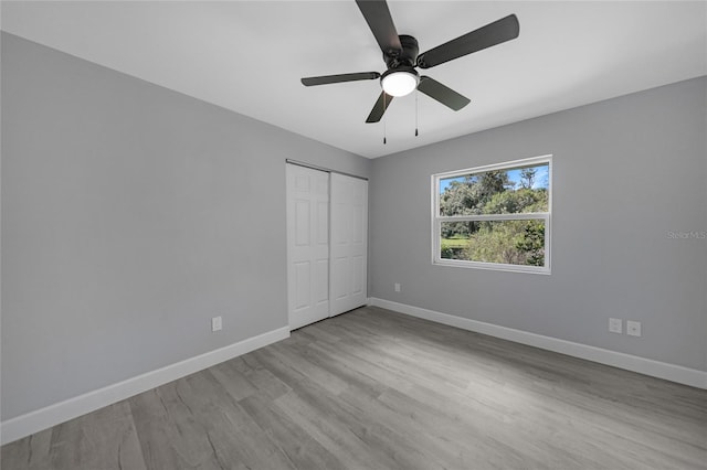 unfurnished bedroom featuring light wood finished floors, a ceiling fan, baseboards, and a closet