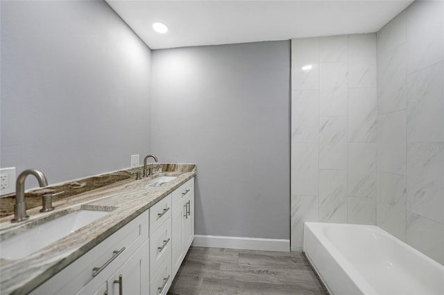 full bath featuring wood finished floors, a sink, baseboards, and double vanity