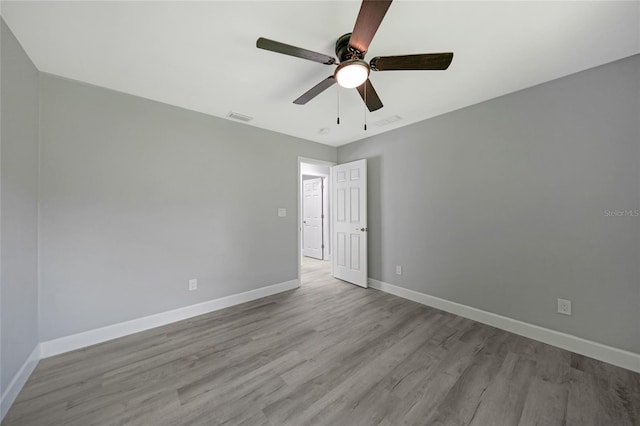 unfurnished room with light wood-type flooring, visible vents, ceiling fan, and baseboards