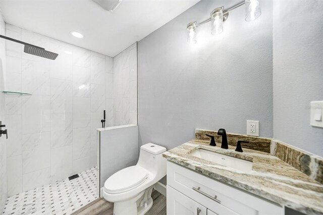 bathroom featuring tiled shower, toilet, and vanity