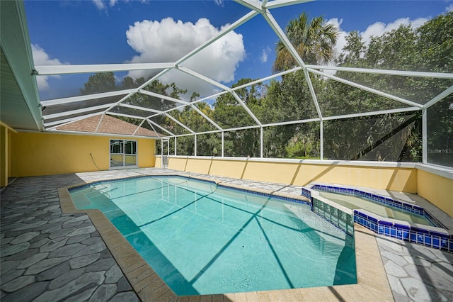 view of swimming pool featuring glass enclosure, a pool with connected hot tub, and a patio