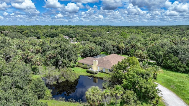 birds eye view of property featuring a water view and a wooded view