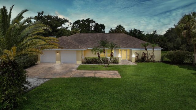 ranch-style home featuring a garage and a yard