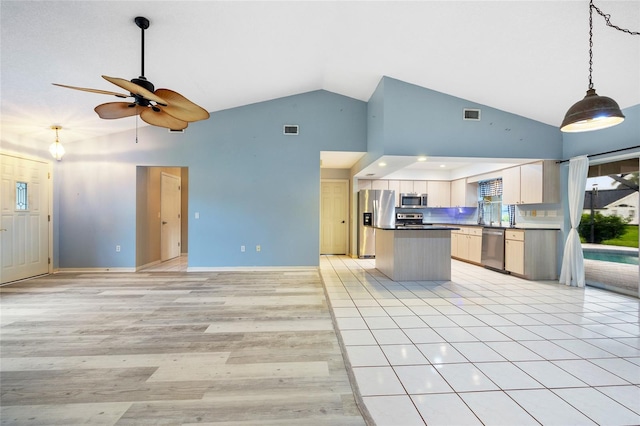 kitchen with light brown cabinetry, light wood-type flooring, stainless steel appliances, ceiling fan, and high vaulted ceiling