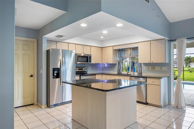 kitchen with appliances with stainless steel finishes, light tile patterned floors, a center island, and light brown cabinetry