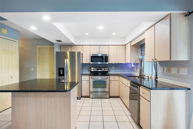 kitchen featuring light tile patterned floors, appliances with stainless steel finishes, a center island, sink, and dark stone counters