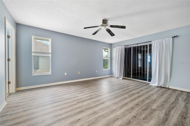 unfurnished room featuring a textured ceiling, a wealth of natural light, ceiling fan, and light hardwood / wood-style floors