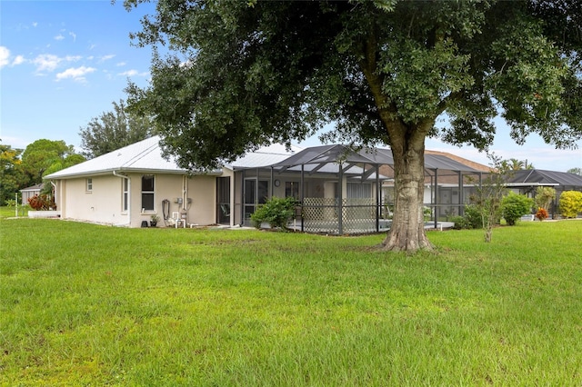 back of property featuring a yard and glass enclosure