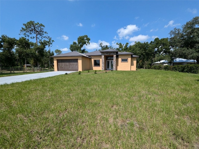 prairie-style home featuring a front yard, fence, an attached garage, stucco siding, and concrete driveway