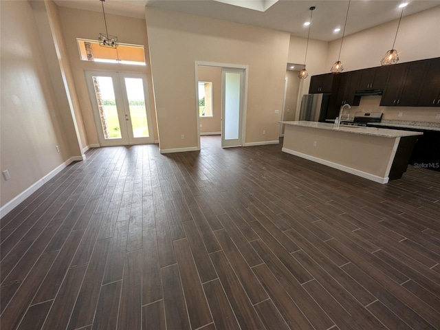 kitchen with under cabinet range hood, a high ceiling, an island with sink, and wood tiled floor