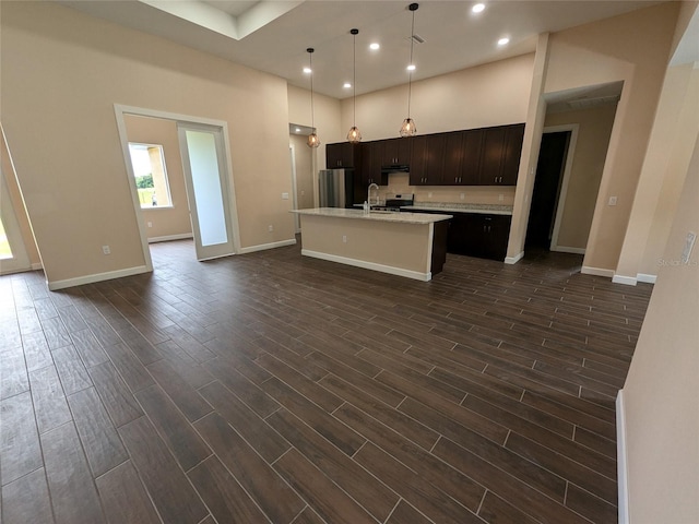 kitchen with wood finish floors, an island with sink, freestanding refrigerator, a sink, and light countertops
