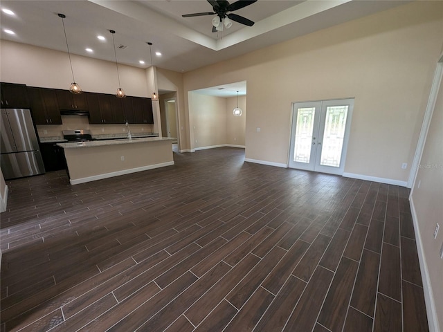 unfurnished living room featuring a towering ceiling, dark wood-type flooring, ceiling fan, and french doors