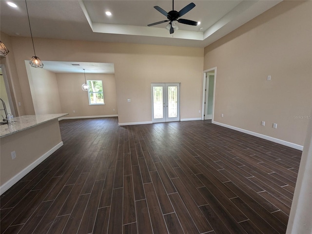 interior space with baseboards, a ceiling fan, a tray ceiling, and wood tiled floor