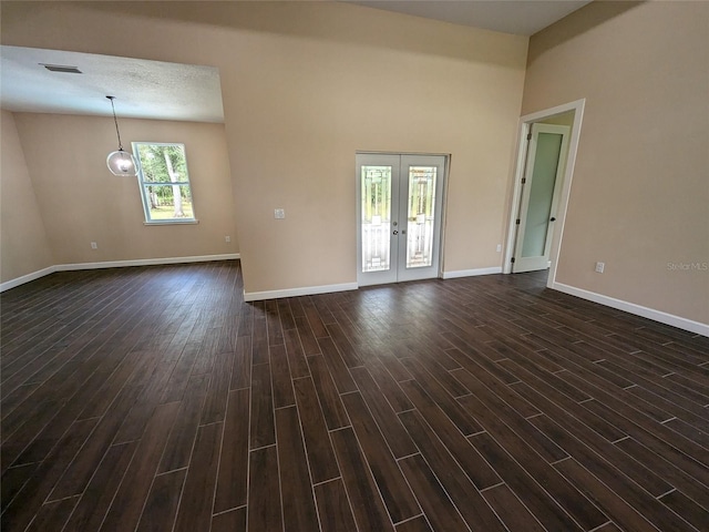 empty room with french doors, a textured ceiling, and dark wood-type flooring