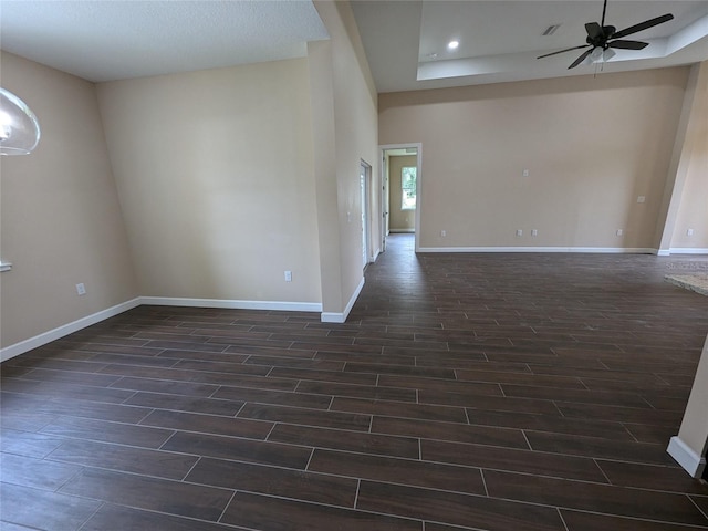 spare room with ceiling fan, a textured ceiling, a towering ceiling, and dark wood-type flooring