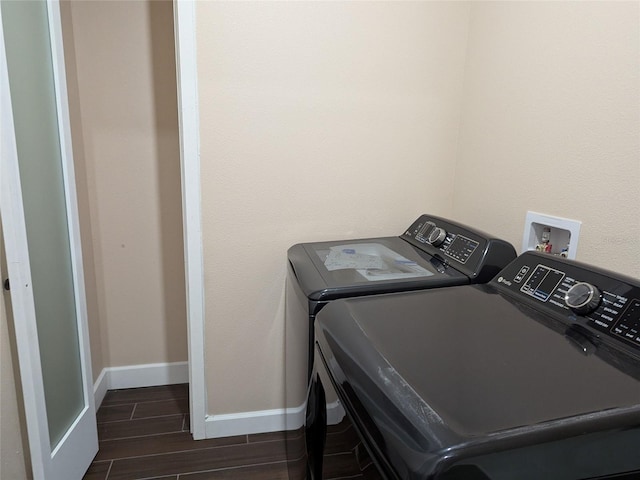 clothes washing area with dark hardwood / wood-style flooring and washing machine and clothes dryer