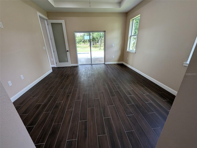 unfurnished room with a raised ceiling and dark hardwood / wood-style floors